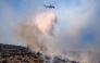 A firefighting helicopter drops water on a wildfire in Haidari, a suburb west of Athens, on July 31, 2026. (Photo by Aris Oikonomou / AFP)