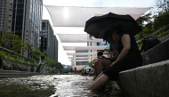 People cool off below sunshades over the Cheonggyecheon Stream in Seoul on August 3, 2026. (Photo by Greg Baker / AFP)