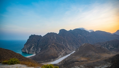A photo of a beach, sea, and mountains in Oman