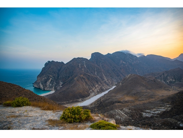 A photo of a beach, sea, and mountains in Oman