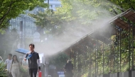 Pedestrians walk along a mist-spraying zone to cool off on a street in Seoul on August 3, 2026, as a scorching heat wave continues to grip South Korea. (Photo by Jung Yeon-je / AFP)