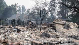 The rubble of a burned out residential home smolders in the Balboa neighborhood of Spokane, Washington, on August 2, 2026. Photo by Erick Doxey / AFP
