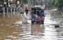 Residents wade through a flooded street following heavy monsoon rains in Guwahati on August 4, 2026. (Photo by Biju BORO / AFP)