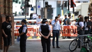 Police community support officers (PCSOs) stand behind cordon tape at Endell road in covent garden, central London on August 5, 2026. Photo by Henry NICHOLLS / AFP