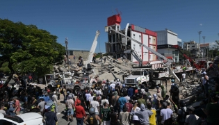 People look for survivors amid the rubble of a collapsed building after an earthquake in Cali, Colombia on August 10, 2026. (Photo by JOAQUIN SARMIENTO / AFP)
