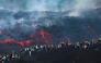 This handout photograph taken by Etna Walk on August 11, 2026 and obtained on August 12, 2026 shows visitors standing next to lava flowing from Mount Etna volcano during an eruption, in Catania, in the Mediterranean island of Sicily. (Photo by Handout / Etna Walk / AFP)