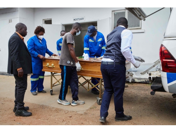 Takemore Malunga (L) watches as pallbearers carry the coffin of his maternal uncle, a victim of the capsized passenger ferry, at the Kariba Hospital mortuary in Kariba, on August 14, 2026. (Photo by Jekesai NJIKIZANA / AFP)