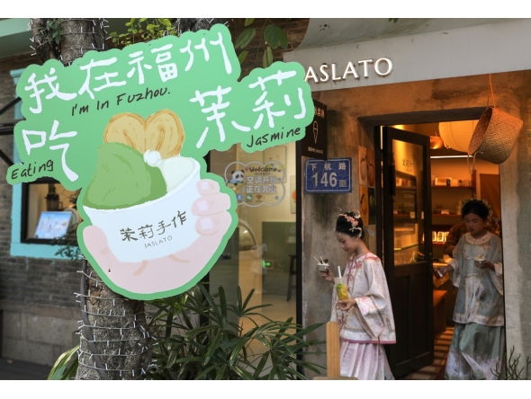 Tourists walk out of a store after buying jasmine tea-flavored gelato at the Shangxiahang historical and cultural block in Fuzhou, southeast China's Fujian Province, Aug. 17, 2026. (Xinhua/Du Xiaoyi)