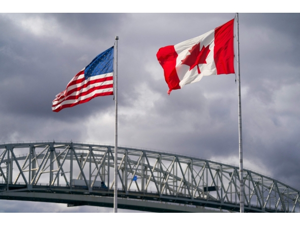 The US and Canadian flags flutter next to the Blue Water Bridge border crossing in Point Edward, Ontario, on October 24, 2025. (Photo by Geoff Robins / AFP)