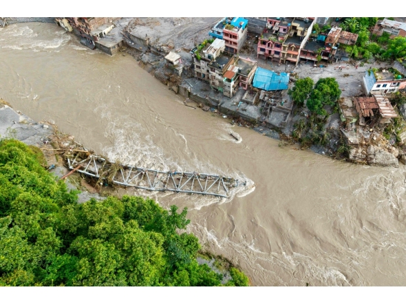 An aerial view shows a collapsed bridge along with houses lying deluged in sludge after flash floods at Devighat, Bidur Municipality in nepal's Nuwakot district on August 27, 2026.  (Photo by Prabin RANABHAT / AFP)