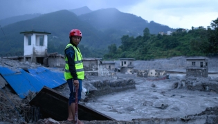 A disaster rescue personnel looks on at the site of damaged buildings in the aftermath of flash floods at Trishuli Bazar in Nepal's Nuwakot district on August 29, 2026. (Photo by MANAN VATSYAYANA / AFP)