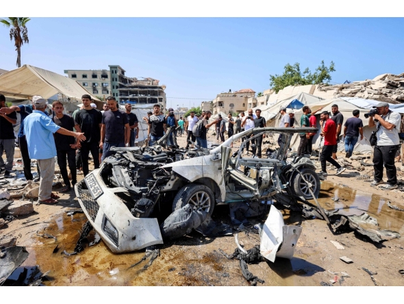 People gather around a destroyed vehicle following an Israeli strike in the Rimal neighbourhood of Gaza City on September 1, 2026. (Photo by Omar AL-QATTAA / AFP)