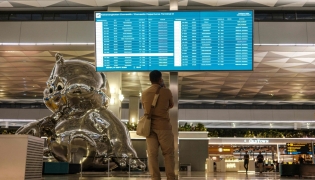 A stranded passenger looks at a flight information screen amid the closure of Soekarno-Hatta International Airport due to the eruption of the Mount Anak Krakatau volcano, in Tangerang on September 7, 2026. indonesia's main airport and several other air travel hubs reopened early on September 8 after days of closure due to ash from a volcanic eruption, the Transport Ministry said. (Photo by Taris HIRZIMAN / AFP)
