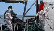 Philippine Coast Guard personnel in protective suits carry a body bag of a victim from the ferry fire to a tent for identification at the port of Borac in Coron, Palawan province on September 13, 2026. Photo by JAM STA ROSA / AFP