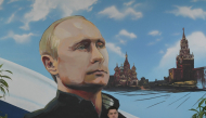 A serviceman of Russia's Emergencies Ministry sits under a mural depicting Russian President Vladimir Putin during Russia's parliamentary election at a polling station in Donetsk, Russian-controlled Ukraine, on September 20, 2026. (Photo by AFP)