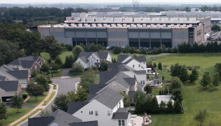 This aerial view shows an Amazon Web Services (AWS) data center adjacent to single-family homes in Stone Ridge, Virginia on August 12, 2026. Photo by Brendan Smialowski / AFP