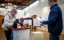 A child accompanied by his parents casts a ballot at a polling station during Latvia's parliamentary elections in Riga on October 3, 2026. (Photo by Wojtek Radwanski / AFP)
