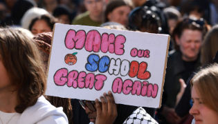 A high school student holds a placard during a gathering amid a nationwide protest movement over school conditions in Saint-Denis, north of Paris, on October 4, 2026. Photo by Kenzo TRIBOUILLARD / AFP