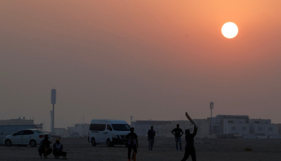 Foreign workers play cricket at sunset in Doha on October 1, 2026. (Photo by KARIM JAAFAR / AFP)
