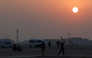 Foreign workers play cricket at sunset in Doha on October 1, 2026. (Photo by KARIM JAAFAR / AFP)

