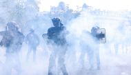 Police officers stand in the smoke during a demonstration of high-school students, in Paris on October 6, 2026, as part of a nationwide protest movement over learning conditions. (Photo by Kenzo TRIBOUILLARD / AFP)