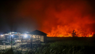 Flames and thick smoke glow against the night sky as a massive wildfire burns near residential structures in the Panarung area of Palangkaraya, Central Kalimantan province, on October 8, 2026. (Photo by REINA / AFP)
