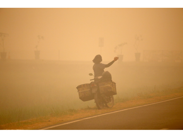 A person takes photos amid thick haze caused by forest and peatland fires in Palangka Raya, Central Kalimantan, Indonesia, Oct. 13, 2026. (Photo by Regina Safri/Xinhua)