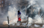 A protester, wrapped in a flag of France, stands in the smoke at Place de l'Opera during ongoing protest action, in Lille, northern France, on October 17, 2026. (Photo by Sameer Al-Doumy / AFP)