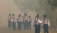 Schoolchildren walk along a smoke-shrouded road in Tegal Arum, Banjarbaru, South Kalimantan, on October 20, 2026, as massive forest and land fires blanket the area in thick haze. (Photo by Muda Sagala / AFP)