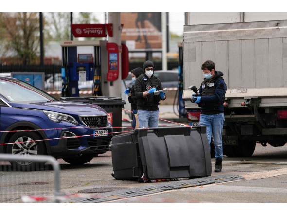 Police officers look at evidences on a site of a petrol station where a man opened fire from his car, killing one person and injuring four others according to police sources, in Trappes, Paris' suburb on October 23, 2026. Photo by Dimitar DILKOFF / AFP
