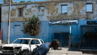 Man leaving prison area while lowering his head due to nearby gunfire in Port-au-Prince, Haiti. AFP file photo.