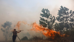 A firefighter battles a fast-moving brush fire amidst heavy smoke in Tegal Arum, Banjarbaru, South Kalimantan, on October 20, 2026. Photo by MUDA SAGALA / AFP