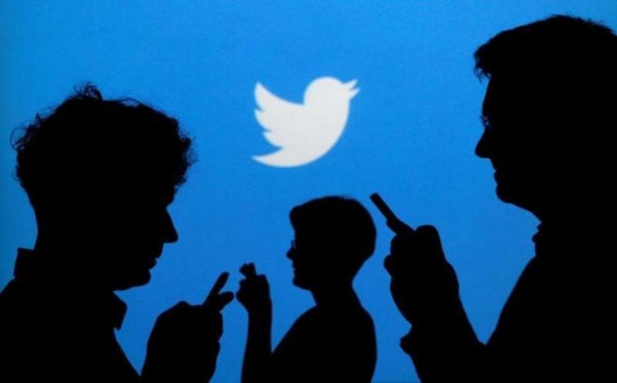 People holding mobile phones are silhouetted against a backdrop projected with the Twitter logo in this illustration picture taken in Warsaw September 27, 2013. REUTERS/Kacper Pempel/Illustration/File Photo