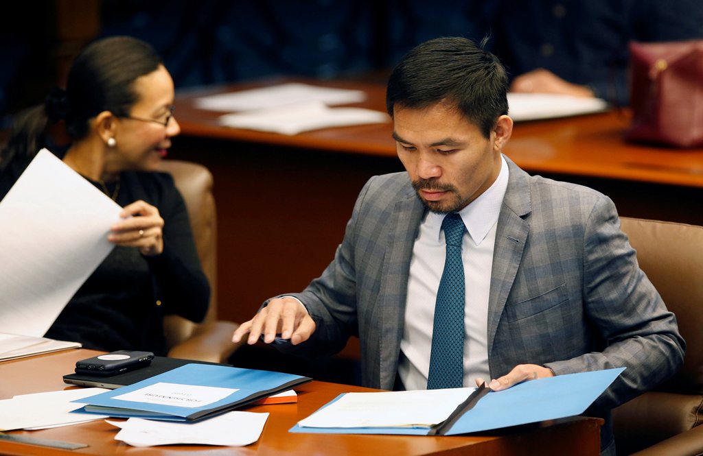 Philippine Senator and boxing champion Manny Pacquiao reads his briefing materials next to fellow Senator Grace Poe, as he prepares for the Senate session in Pasay city, Metro Manila, Philippines. (REUTERS/Erik De Castro/File Photo)