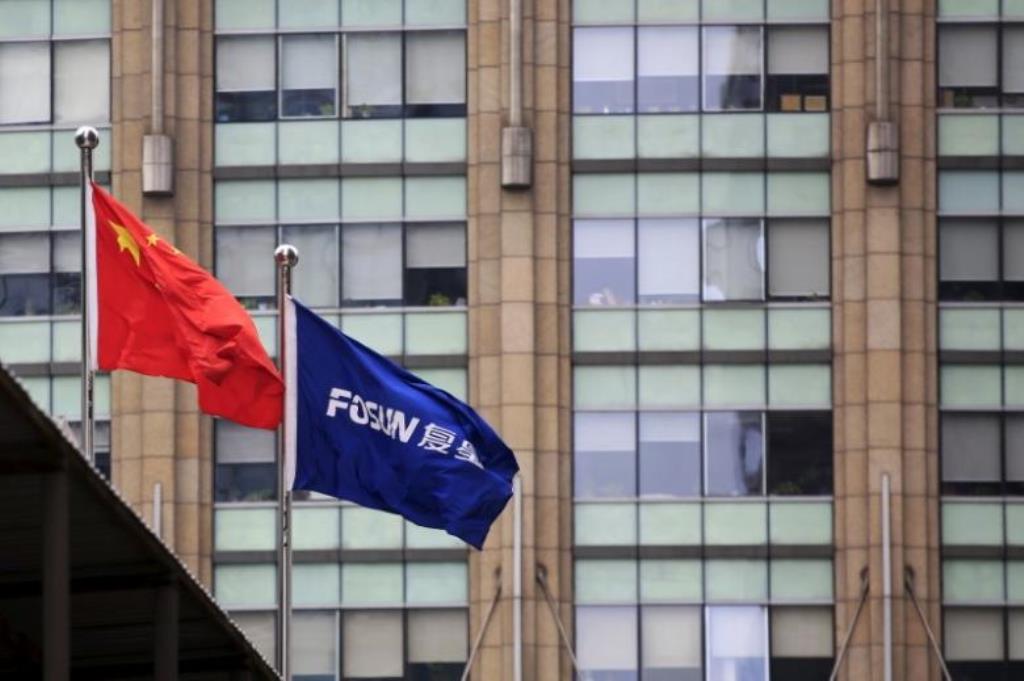 A Chinese national flag (L) flies in front of a building of the headquarters of Fosun International, in Shanghai, China. REUTERS/Aly Song