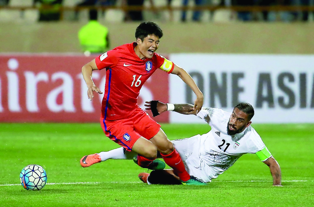Iran’s Ashkan Dejgah (right) tackles South Korea’s Ki Sung-yueng during the 2018 World Cup qualifying football match at the Azadi Stadium in Tehran yesterday.