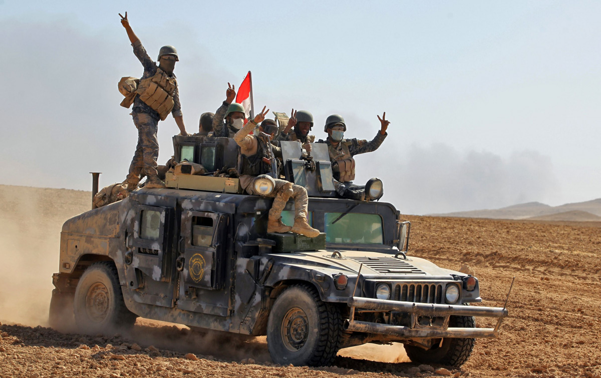 Iraqi government forces flash the sign for victory as they advance towards the village of Tal al-Shawk on the eastern bank of the Tigris river on October 20, 2016, during the ongoing operation to retake Mosul from the Islamic State (IS) group. The operati