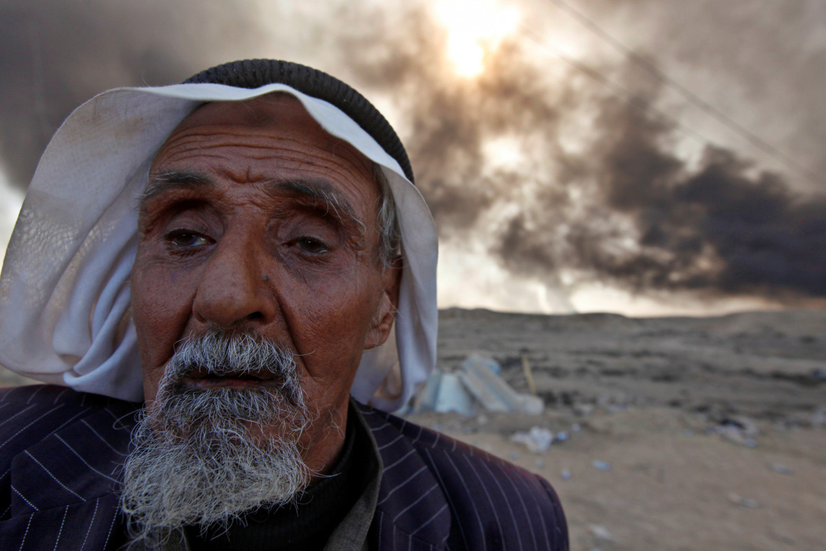 A man returns to his village after it was liberated from Islamic State militants, south of Mosul in Qayyara, Iraq, October 22, 2016. The fumes in the background are from oil wells that were set ablaze by Islamic State militants. REUTERS/Alaa Al-Marjani