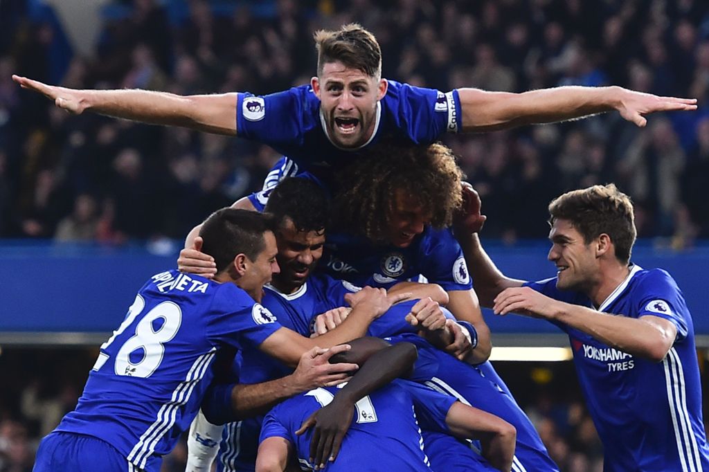 Chelsea's English defender Gary Cahill (top) jumps onto the huddle to join the celebrates after Chelsea's French midfielder N'Golo Kante scored their fourth goal during the English Premier League football match between Chelsea and Manchester United at Sta