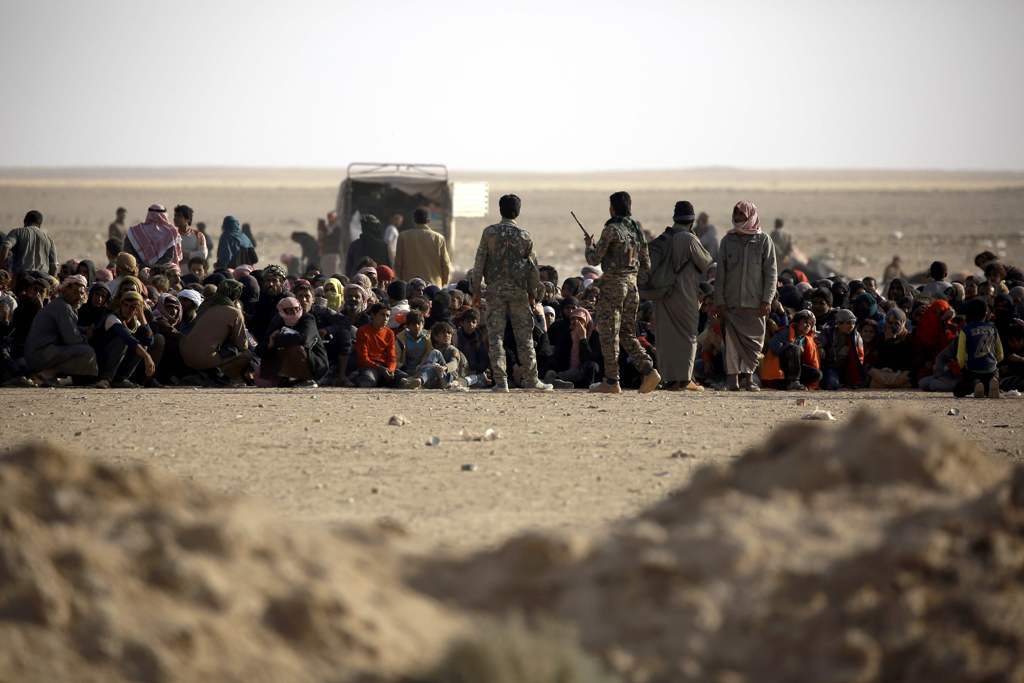 Syrian Democratic Forces stand guard as Iraqi refugees who fled Mosul, the last major Iraqi city under the control of the Islamic State (IS) group, due to clashes during the ongoing assault by the Iraqi government forces to retake the city, wait to enter 