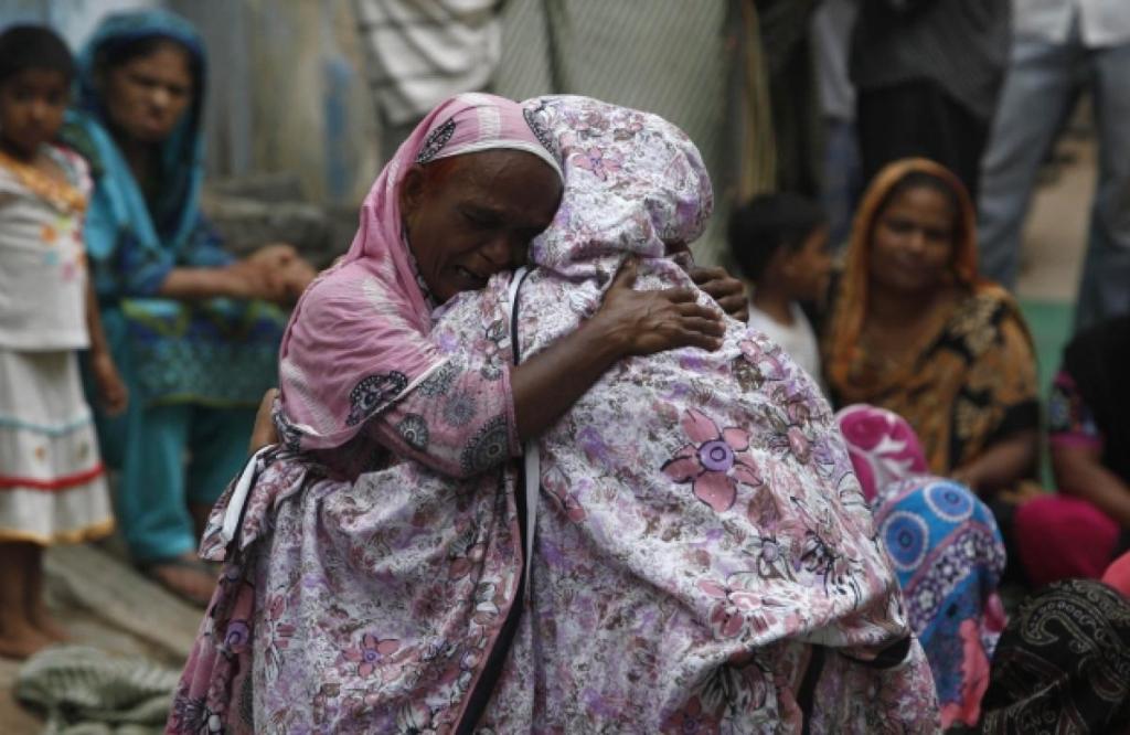 Family members comfort each other as they mourn the death of Salamat Maseh, a father of two who died after consuming locally-made toxic liquor in Karachi, Pakistan. (AKHTAR SOOMRO/REUTERS) 2013.