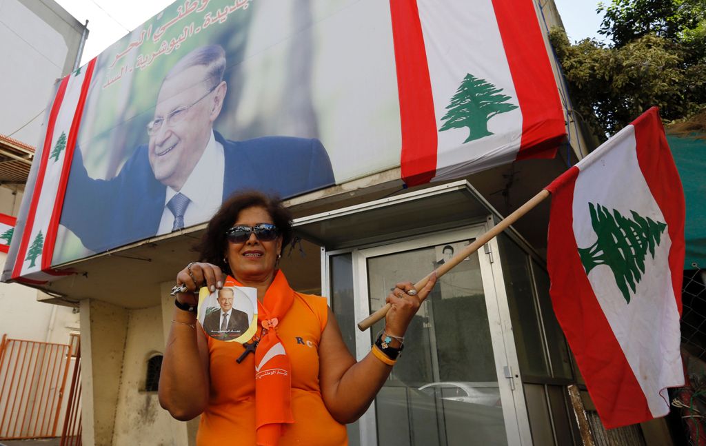 A supporter of Lebanese presidential candidate Michel Aoun holds his portrait and the Lebanese flag ahead of a parliament session expected to elect the ex-general as president and end a political stalemate of more than two years, as they gather in Jdeidah