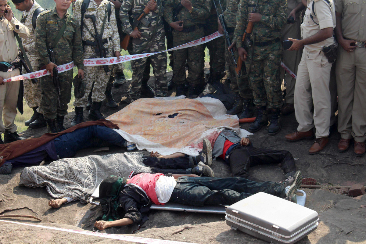Indian police gather alongside the bodies of SIMI activists, who allegedly escaped from Central Jail in Bhopal and were killed in highly suspicious circumstances by Special Task Force police at the hillocks of Acharpura village, near Bhopal on October 31,
