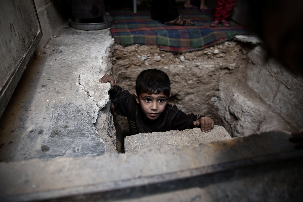 A Syrian boy climbs out of Abu Omar's shelter in the rebel-held town of Douma, on the eastern outskirts of Damascus, on October 30, 2016.  AFP / Sameer Al-Doumy