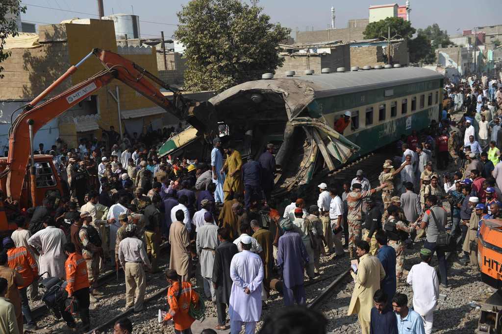 TOPSHOT - Pakistani bystanders watch the rescue work at the site of a collision between two trains in Karachi on November 3, 2016. / AFP / RIZWAN TABASSUM