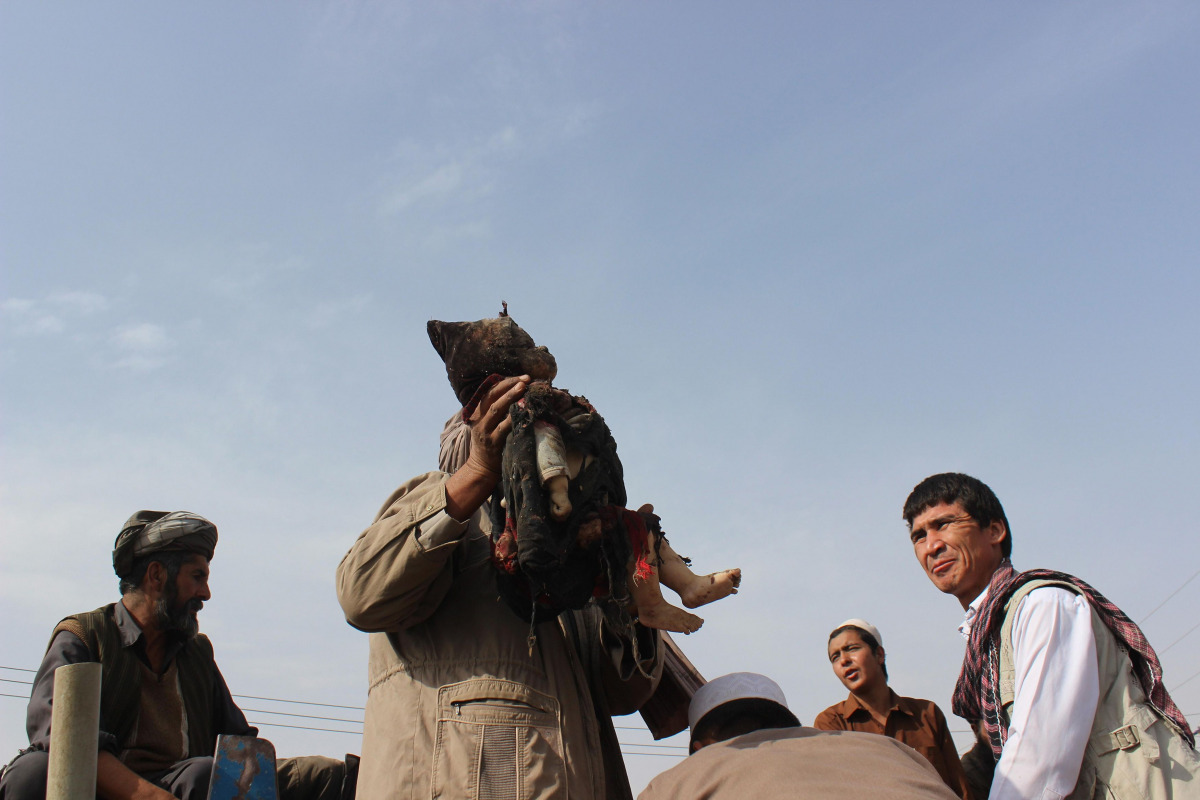An Afghan man carries the dead body of a child following a NATO coalition airstrike on the outskirts of Kunduz on November 3, 2016. 30 Afghan civilians were killed in an airstrike in Kunduz, Afghan officials said on November 3. (AFP / BASHIR KHAN SAFI)
