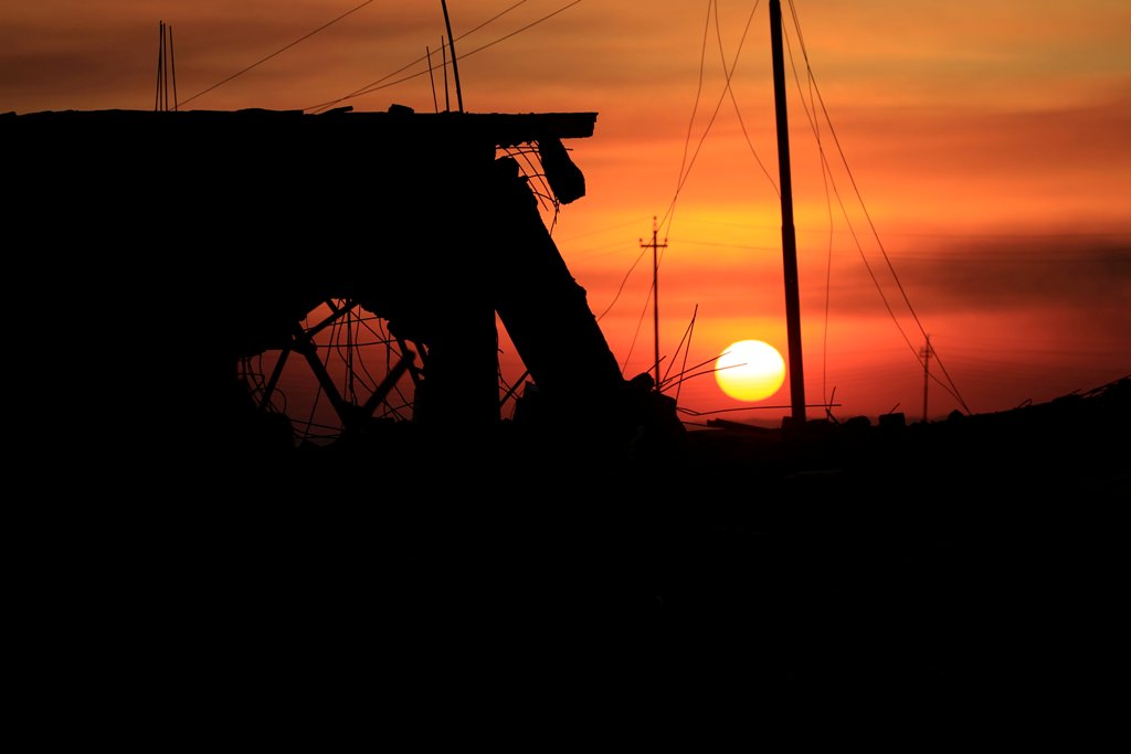A sunset is pictured near a destroyed building in Bartella, east of Mosul, Iraq November 3, 2016. Picture taken November 3, 2016. REUTERS/Zohra Bensemra