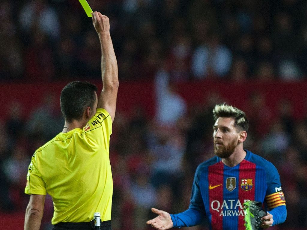 Barcelona's Argentinian forward Lionel Messi (R) is shown a yellow card during the Spanish league football match Sevilla FC vs FC Barcelona at the Ramon Sanchez Pizjuan stadium in Sevilla on November 6, 2016. / AFP / JORGE GUERRERO