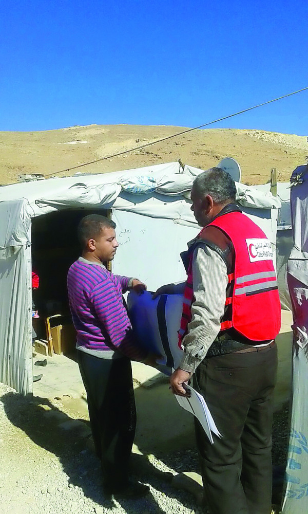 A QRCS volunteer distributing aid.