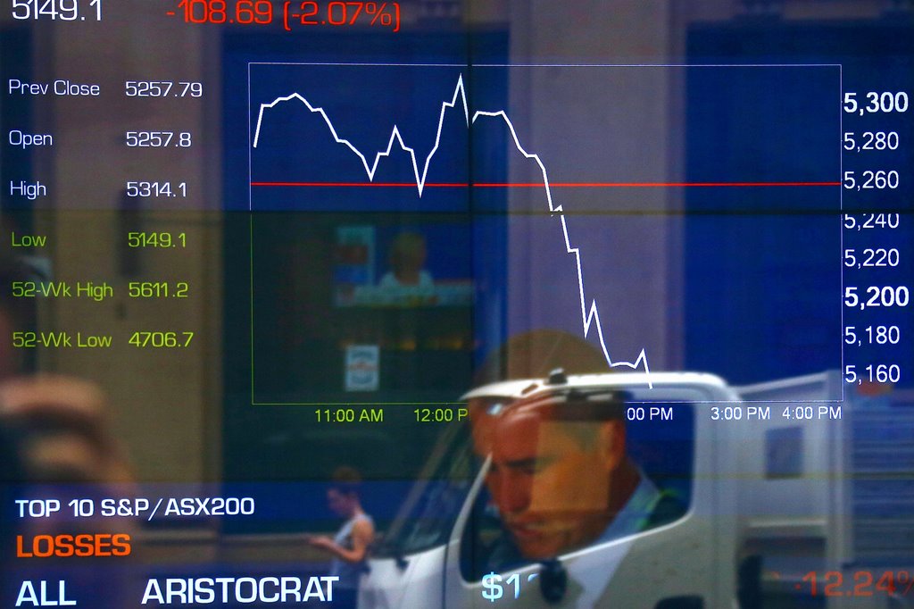 A pedestrian and financial journalist look at their phones as they are reflected in a window in front of a board displaying stock prices at the Australian Securities Exchange (ASX) in Sydney, Australia, November 9, 2016. REUTERS/David Gray